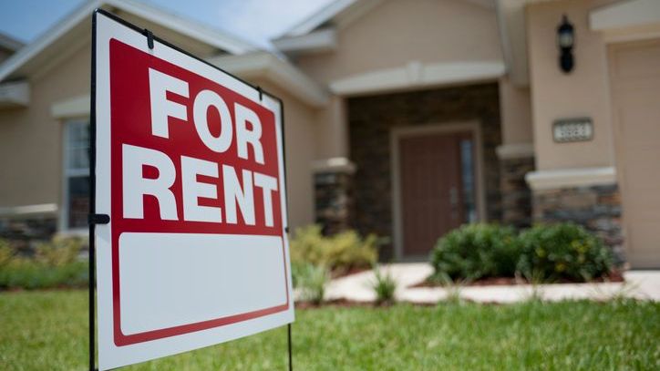 A for rent sign sits outside of a single family home owned by a real estate investor. 